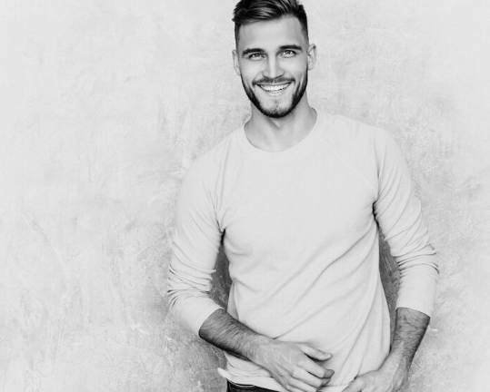 Photo en noir et blanc d'un jeune homme souriant aux cheveux courts